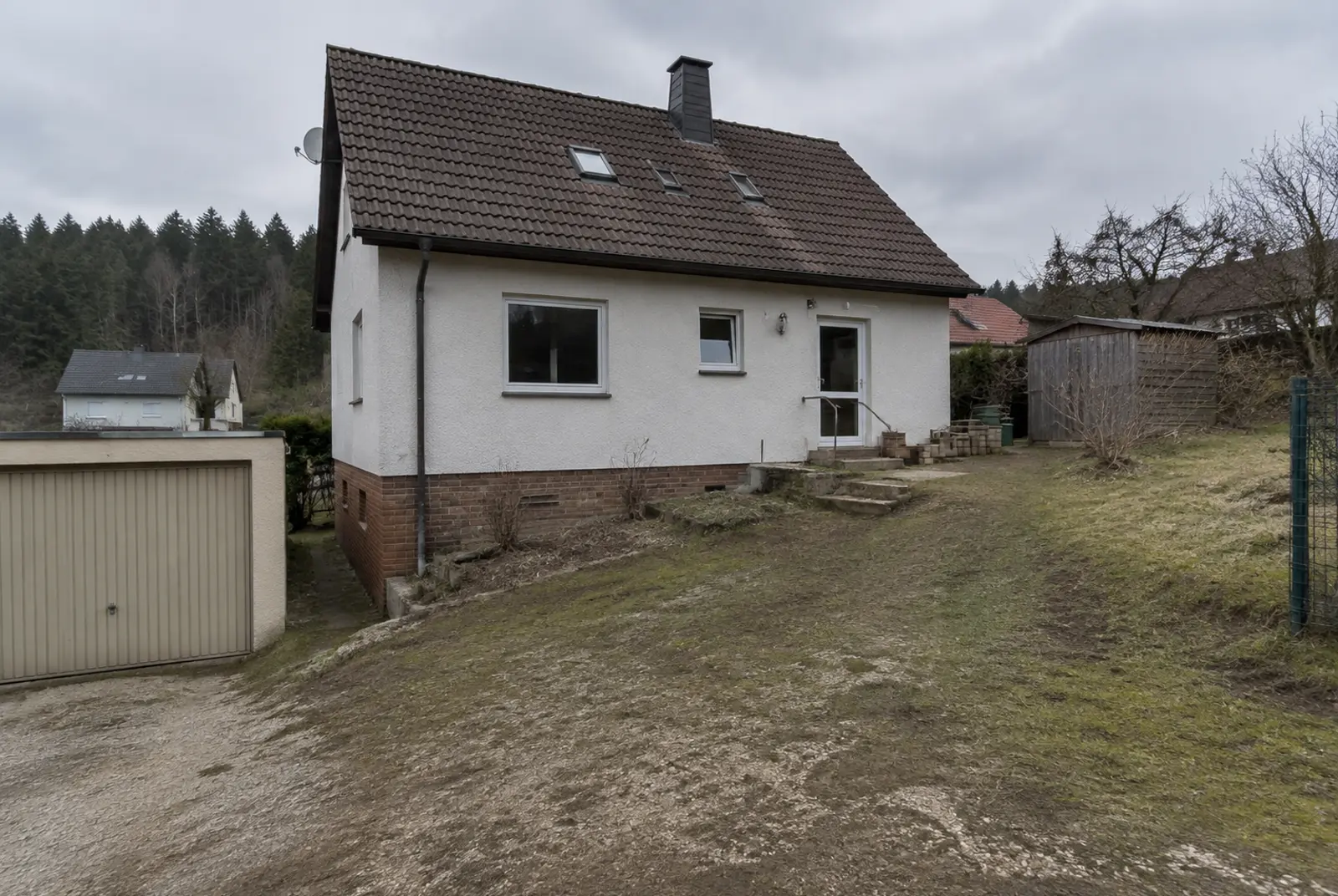 Schräge, unbefestigte Fläche hinter einem Wohnhaus